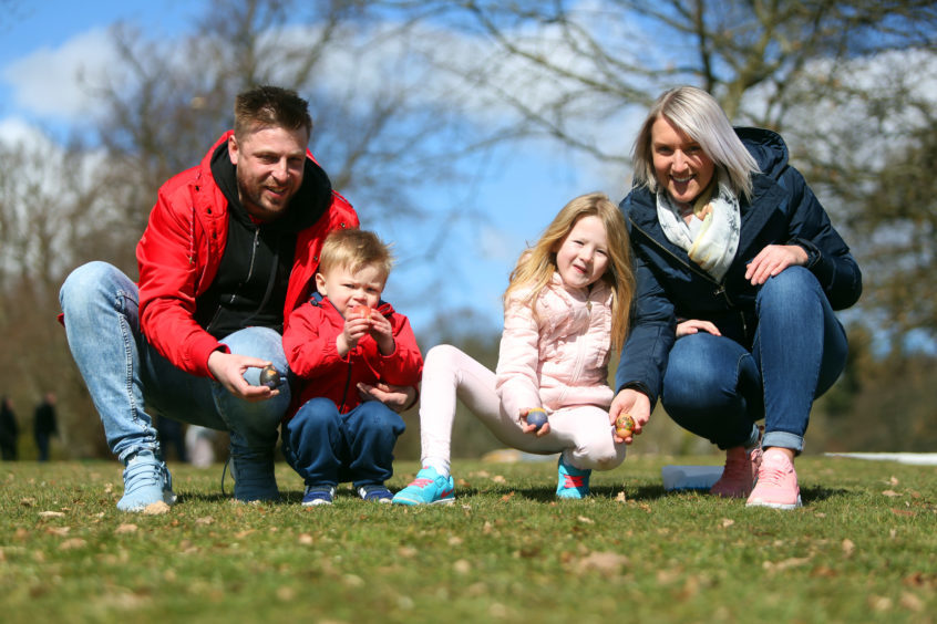 Scott, Connor and Layla Ferrier with Dee Chard rolling their Easter eggs at Camperdown Park.