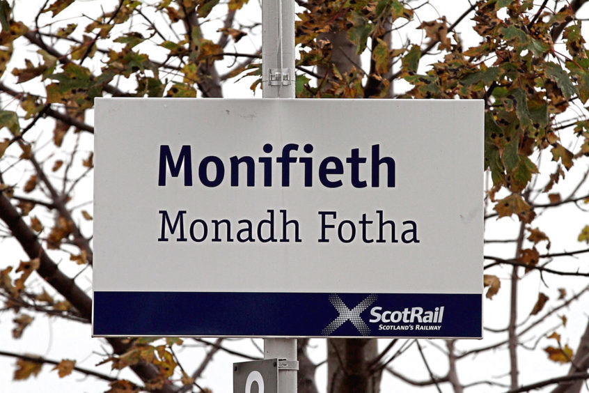 Photo shows a ScotRail sign for the town of Monifieth with the Gaelic translation - Monadh Fotha.