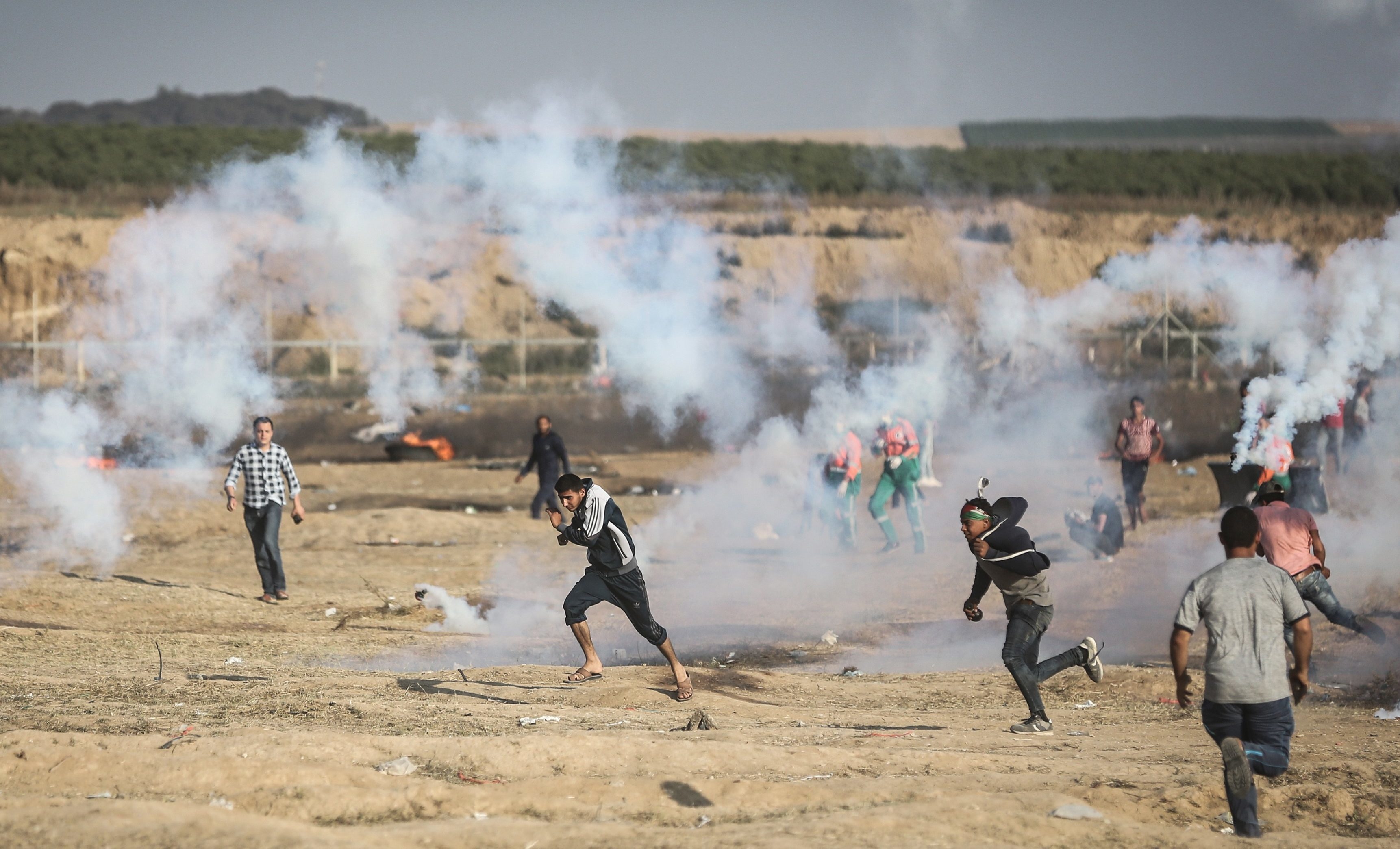 Palestinian protesters run from tear gas canisters fired by Israeli security forces in Gaza City.