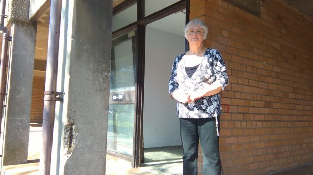 Cecelia Proctor stands beside a broken door and an eroded pillar at the Nicol Street flats complex.