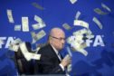 Then FIFA president Sepp Blatter has banknotes thrown at him by British comedian Simon Brodkin in July 2015 (pic: Ennio Leanza/Keystone via AP).