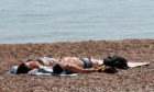 A couple relax in the sunshine on the beach at the start of the June heatwave in 2018.