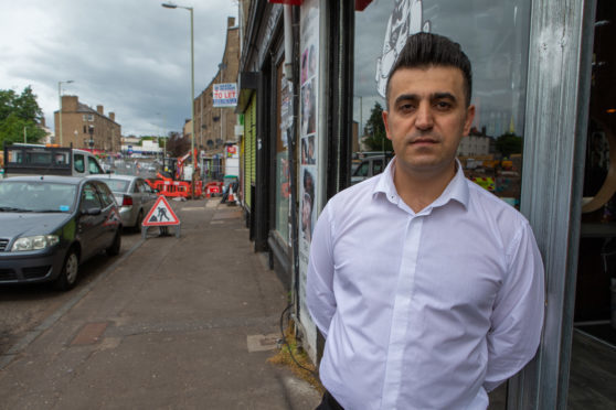 Yousif outside his barber's shop on Strathmartine Road.