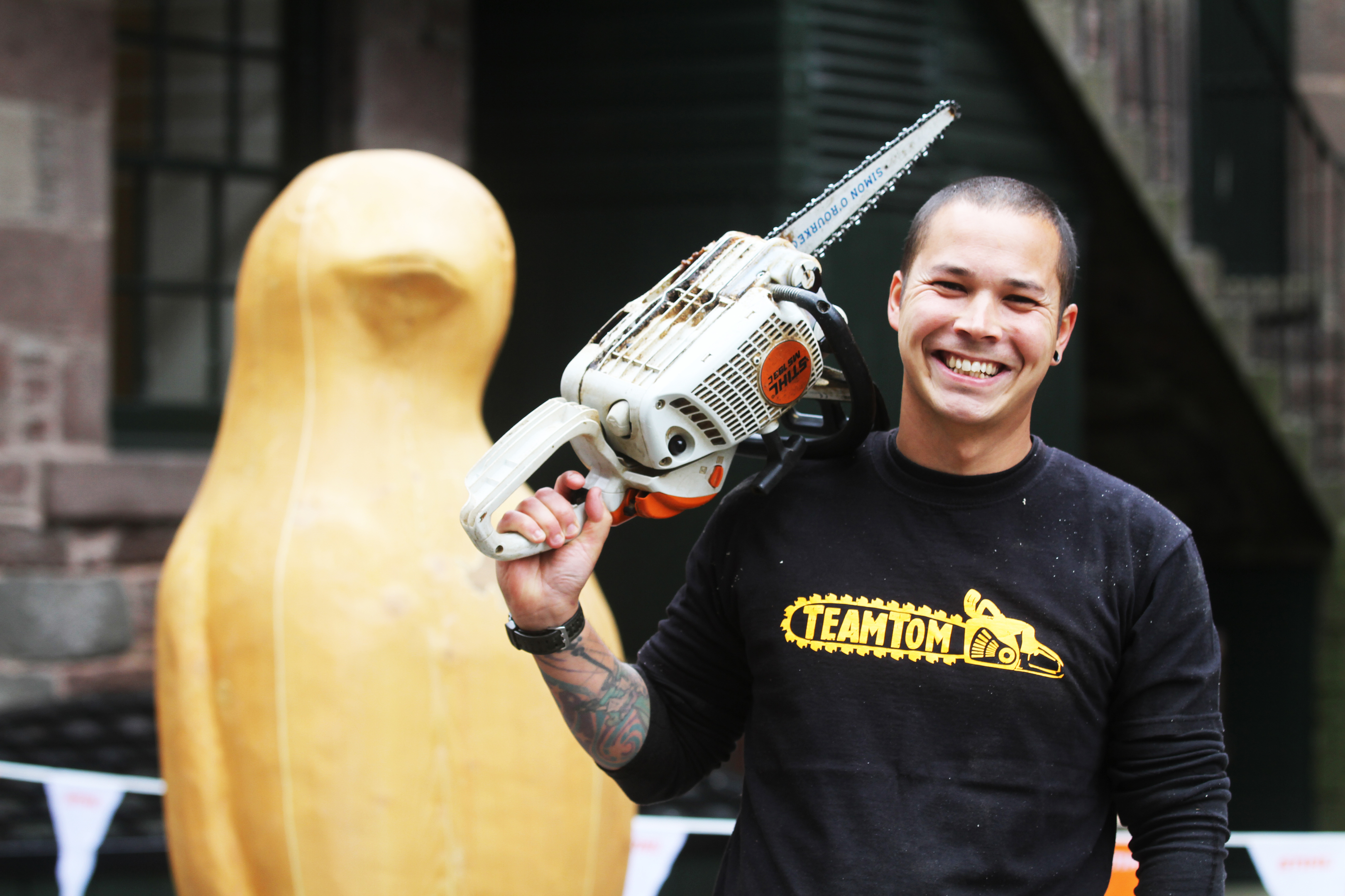 Chainsaw artist Tom Harris-Ward with the sculpture he created for the Maggie's Penguin Parade.