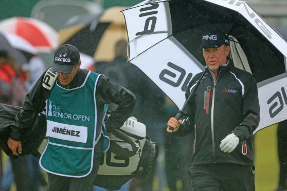Miguel Angel Jimenez shelters from the rain during the final round of the Senior Open.