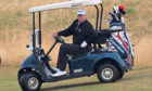 US President Donald Trump drives a golf buggy on his golf course at the Trump Turnberry resort in South Ayrshire.