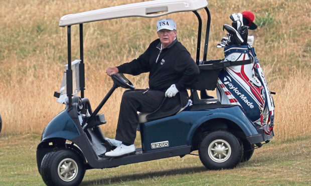 US President Donald Trump drives a golf buggy on his golf course at the Trump Turnberry resort in South Ayrshire.
