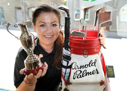 Karina MacKinnon, manager of the Golf Shop of St Andrews, with Arnold Palmer's golf bag which is on display in the shop window for the duration of the Senior Open