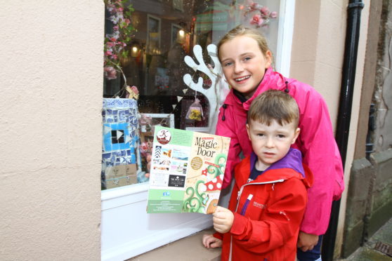 Courier Angus news-job CR0002748-   Mya Duncan Walker (11) & Cairn Hamilton (4) looking in shop windows to find the magic doors as part of the Magic Door Tour in Kirriemuir,saturday 28th july.