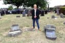 Councillor John O'Brien beside some of the damaged head stones.