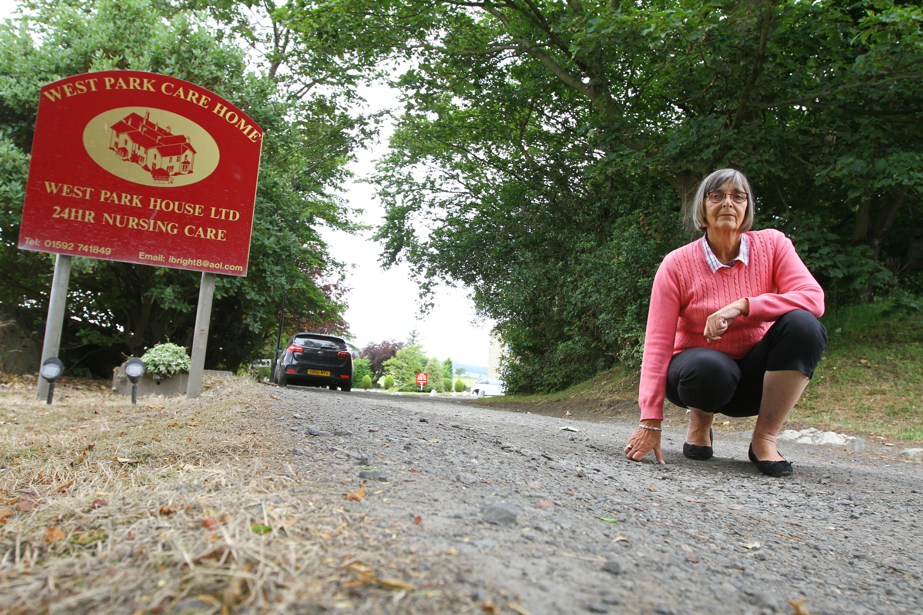 Courier Fife news-job CR0002411- Esther McLaren pictured on the road up to West Park Care Home in Leslie Fife which is badly potholed, and hervfather George has had to reduce his visits to see  wife margaret because of the state of the road.friday 13th July.