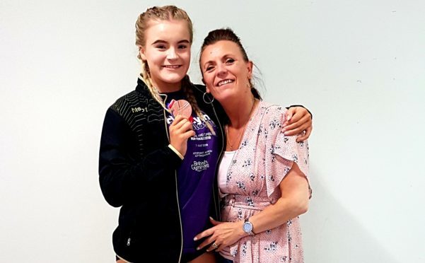 Tegan Gaffrey showing off her medal, accompanied by her mum, Cordelia.