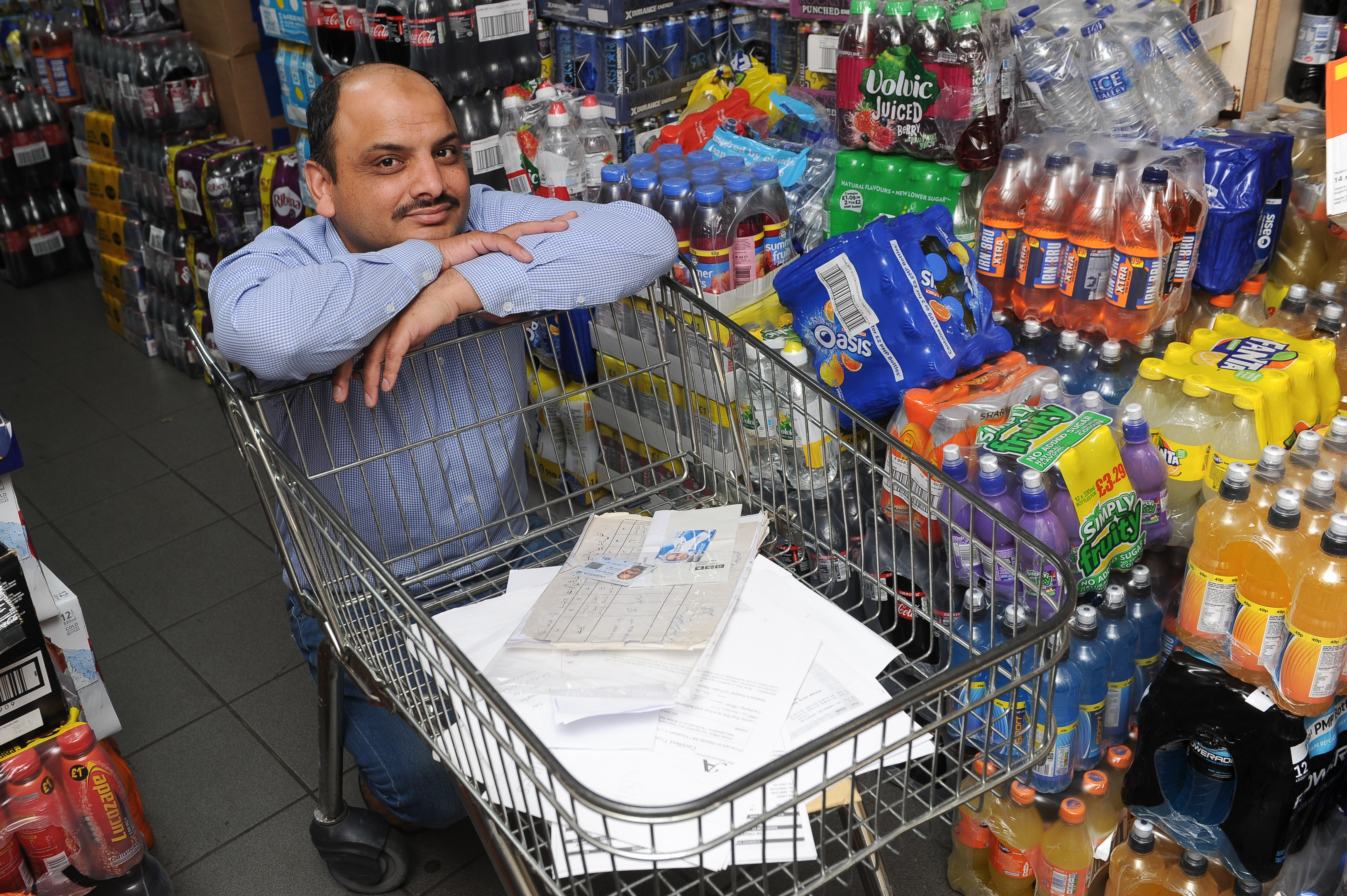 Hassan Majid Mirza in the Fairdeal Store,  Dundee, with a trolley containing documentation he has used in support of his application.