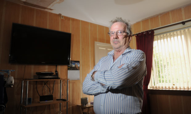 Robert Young in his living room which has been disrupted with dampness