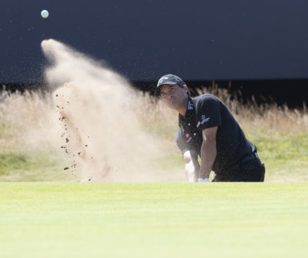Kevin Kisner splashes out of the bunker at the final hole at Carnoustie on his way to a leading 66.