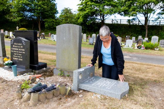 Mrs Ward examining the damage to her husband's headstone
