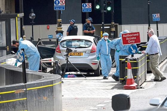 Forensic officers by the car that crashed into security barriers outside the Houses of Parliament.