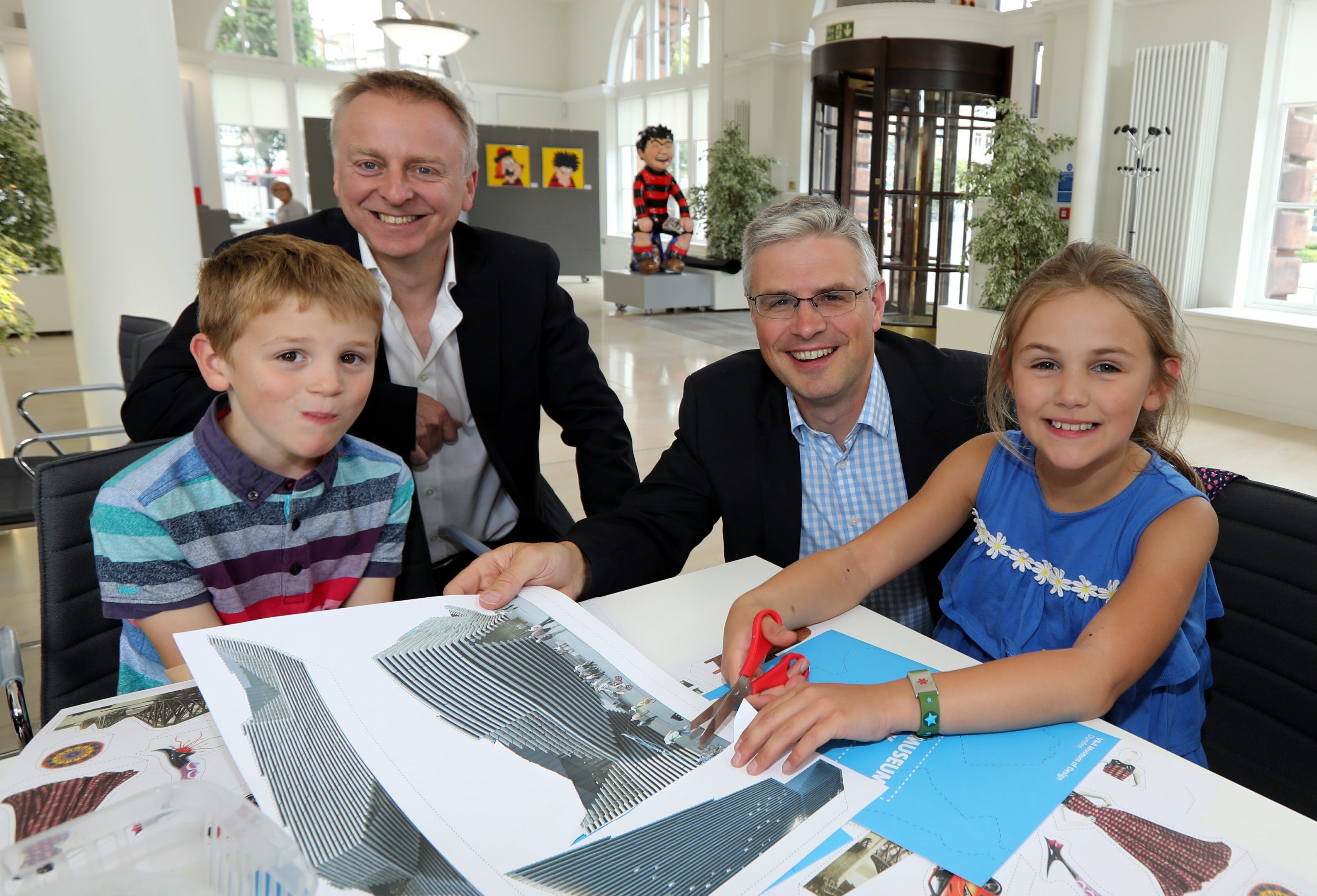 Philip Long and David Thomson helping Jamie and Emily Thomson with their pop-up books.