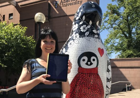 Suzanne Scott tries the AR app with her penguin outside Abertay University.