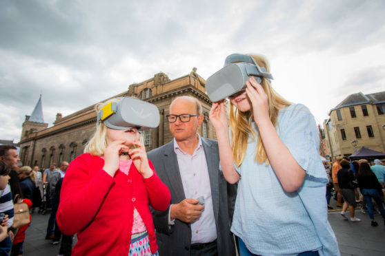 Sisters Flora Wylie (aged 8, left) and Erin Wylie (aged 12, from Perth) wearing the headsets alongside Chris Perry (from  international architectural firm Mecanoo).