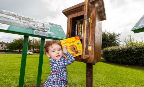 Two-year-old Carsyn Smart checks out a book from The Wee Library