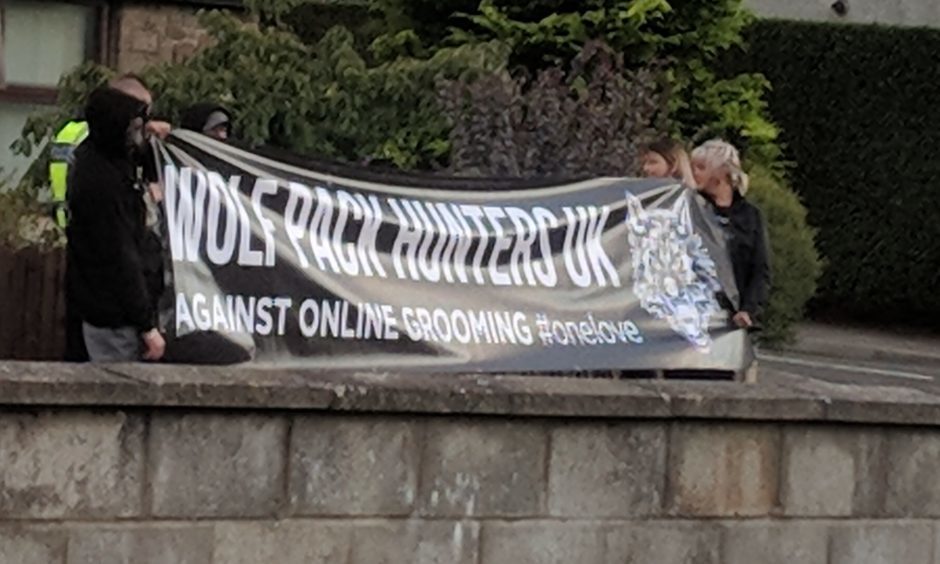 People with a banner which reads 'Wolf pack hunters UK, against online grooming'