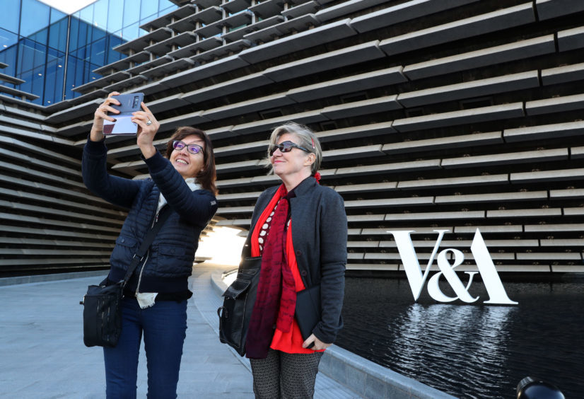 Two women take a selfie outside the finished exterior of the new eighty million pound V&A Dundee museum.