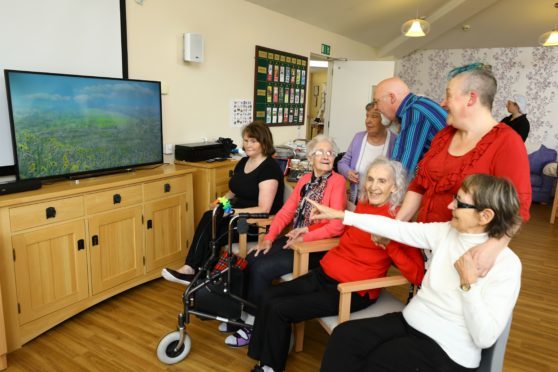 John Phillips, back centre, and Emma Ainsley, back right, both from Harmonious Place, with some of the residents watching the video, at Janet Brougham House in Dundee.