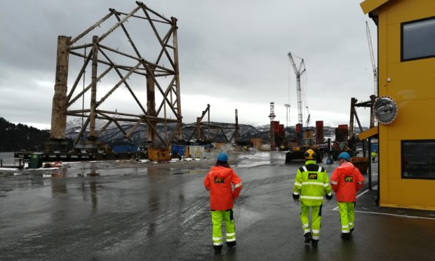 A former North Sea oil rig towers over a working  decommissioning yard