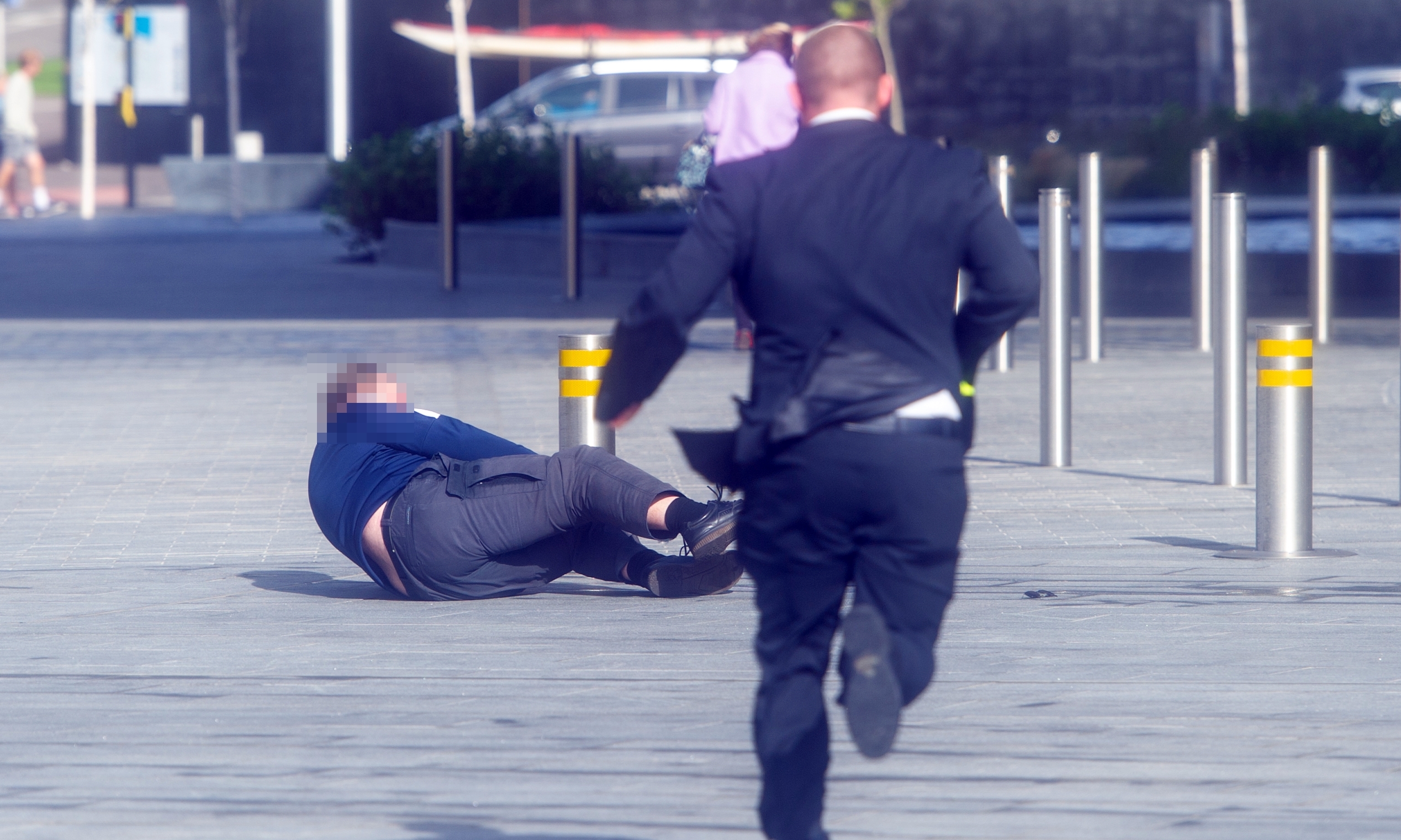 A man rushes to help after another man was swept off his feet by the strong wind outside V&A Dundee.