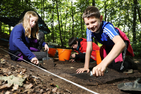 Eleanor Kinmond, Daniel Cave and Jack Roberts digging for items.