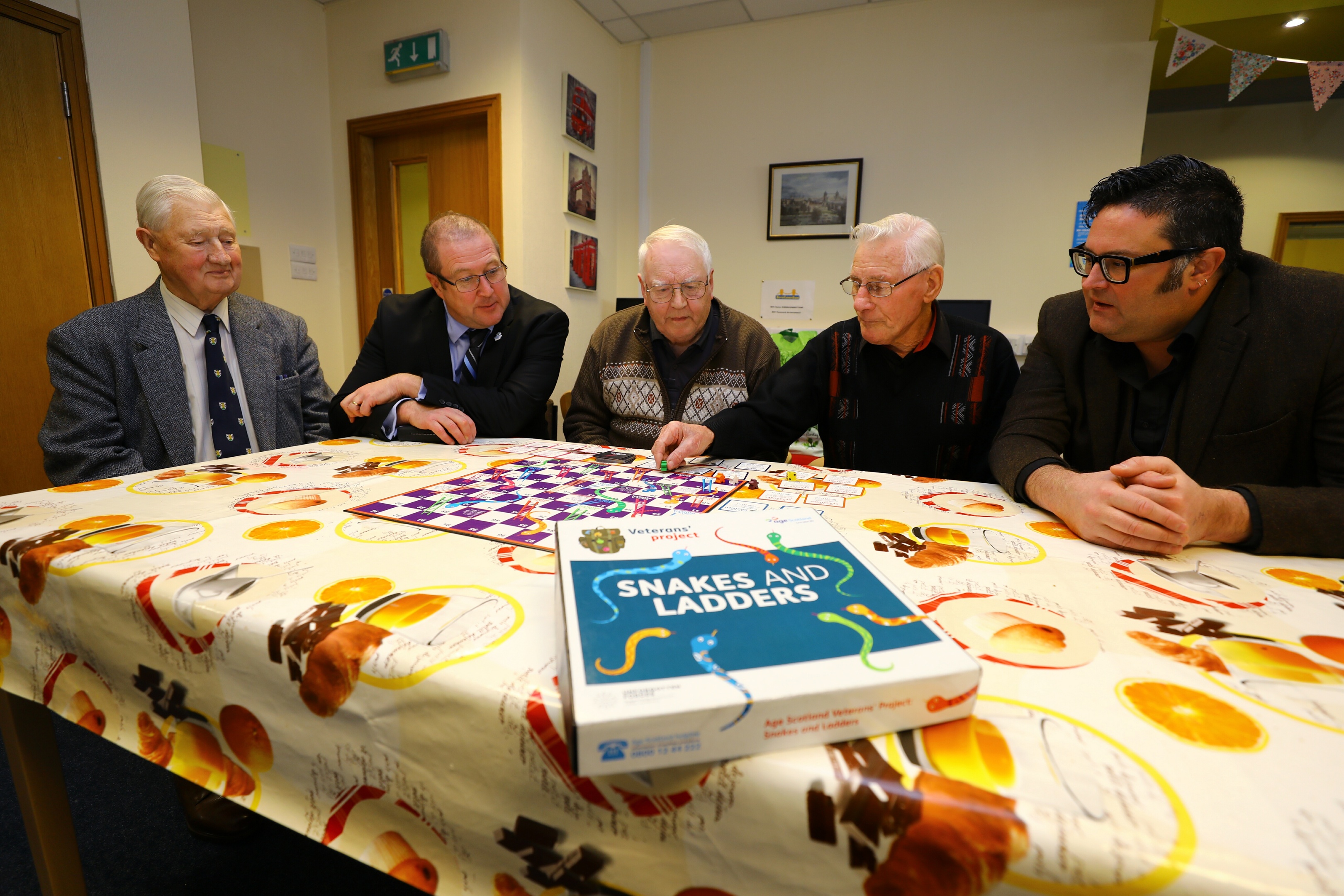 Veterans Minister Graeme Dey MSP, 2nd left, playing a specially adapted game of snakes and ladders for veterans, during his visit to the Dementia Hub, with L/R, Ian Bruce, John Duncan, James Wallace and Graham Galloway - Kirrie Connections