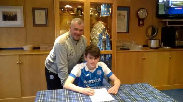 Finn Regan puts pen to paper with Saints head of youth development Alistair Stevenson looking on.