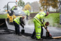 Workmen laying the road that contains plastic mixed with bitumen.