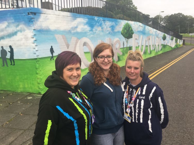 Jen Anderson, Kerry Wilson and Carol Hunter beside a mural painted on a campus wall in 2018