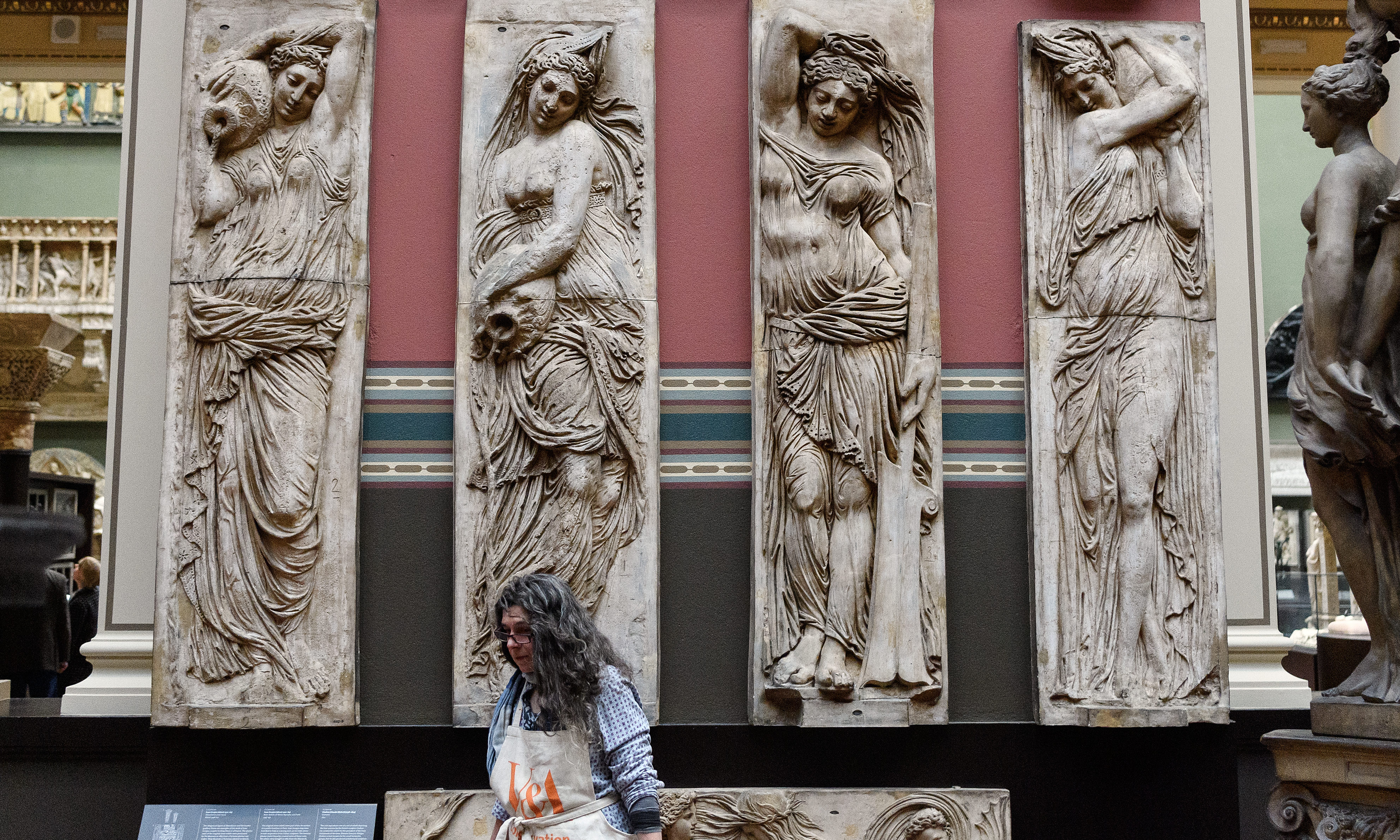 A conservator stands beneath a series of casts.
