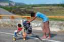 A man pushes a child in a stroller along the highway as a thousands-strong caravan of Central Americans continues its slow journey toward the U.S. border, between Niltepec and Juchitan, Oaxaca state, Mexico.