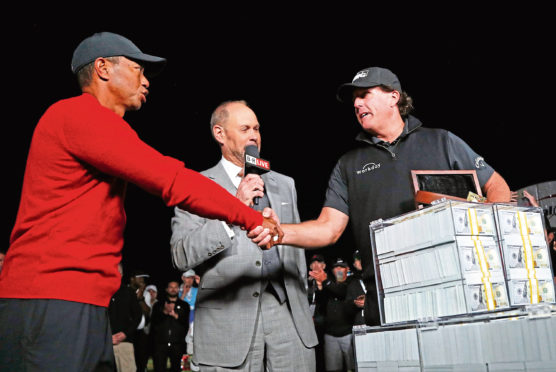 Tiger Woods, left, shakes hands after losing a golf match to Phil Mickelson, right, at Shadow Creek golf course, Friday, Nov. 23, 2018, in Las Vegas. (AP Photo/John Locher)