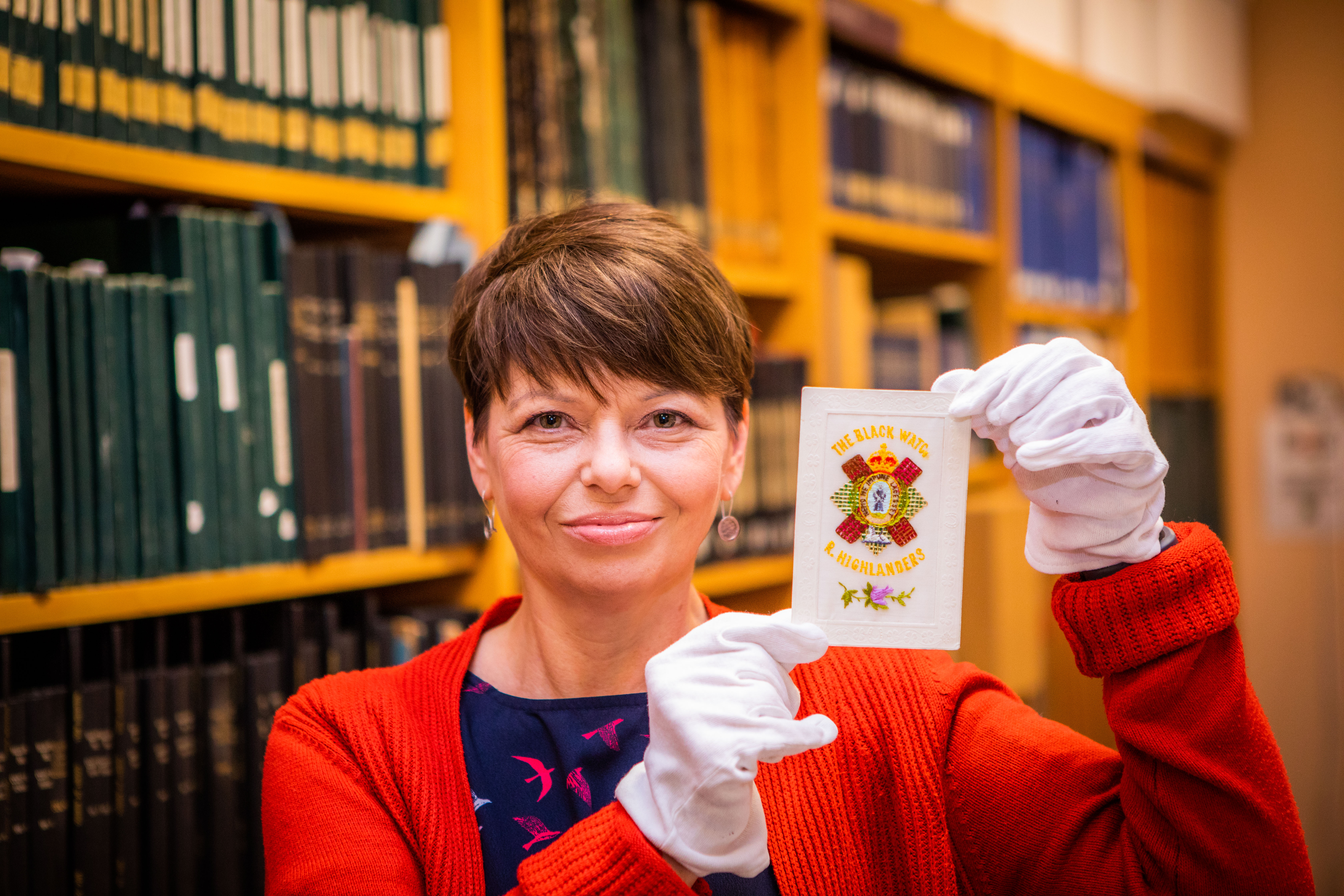 Archivist Lorna Westwater with one of the silk embroidered First World War postcards - a Black Watch design.