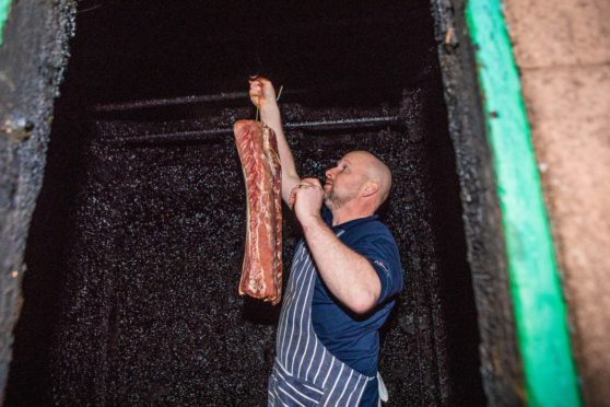 Butcher John Morrison removes a side of smoked bacon from the original smokehouse.