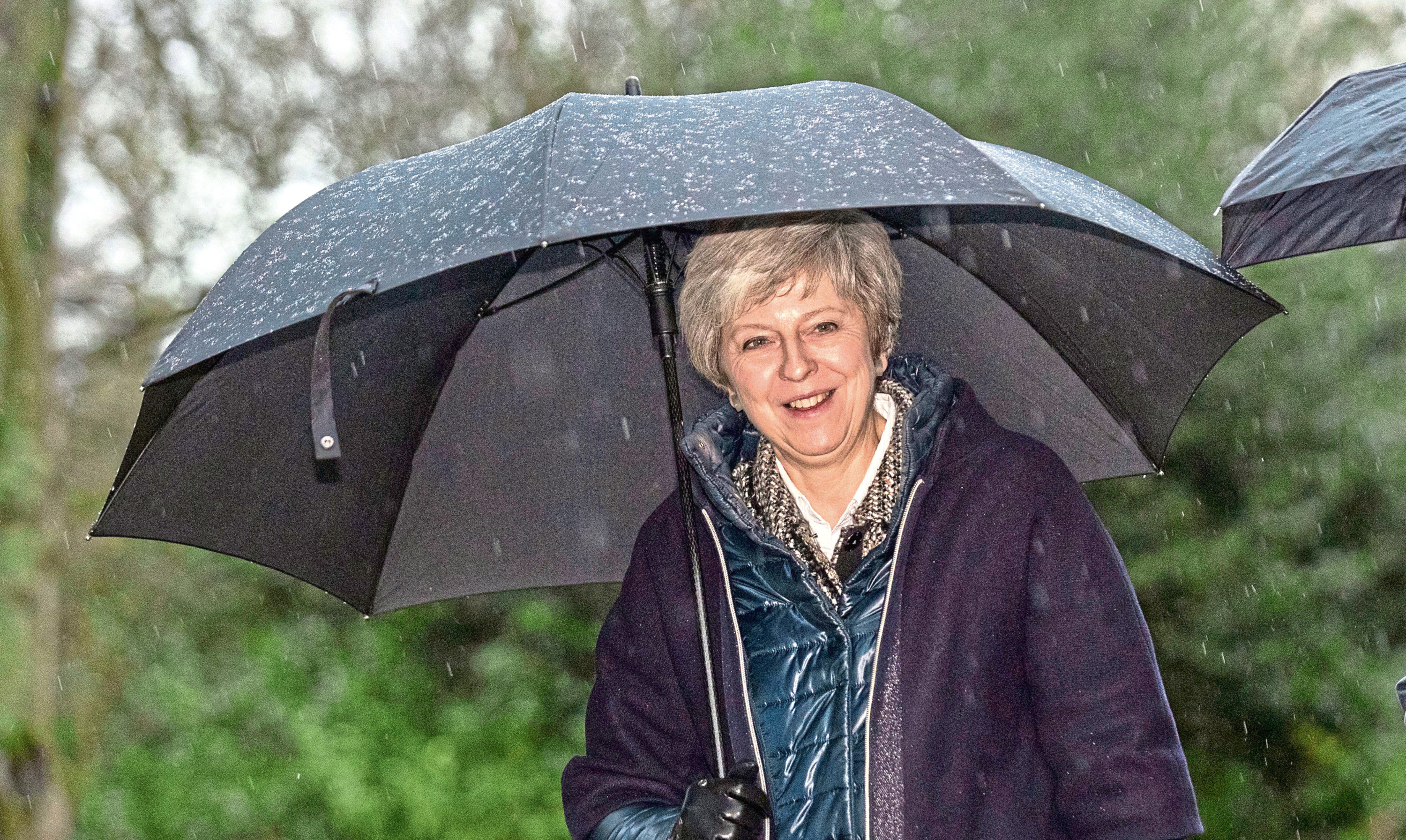 Prime Minister Theresa May shelters from the rain