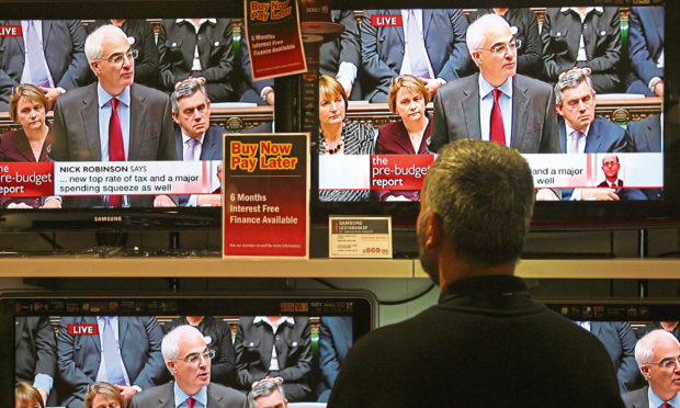Albert Ram, a salesman at Ask electrical retailers on Tottenham Court Road, cleans the screens of televisions showing the Chancellor of the Exchequer, Alistair Darling, live in Parliament delivering his Pre-Budget Report on November 24, 2008 in London, England.