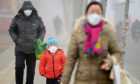 Citizens wearing masks walk on the road which is blanketed by heavy smog on January 5, 2017 in Jinan, Shandong Province of China.
