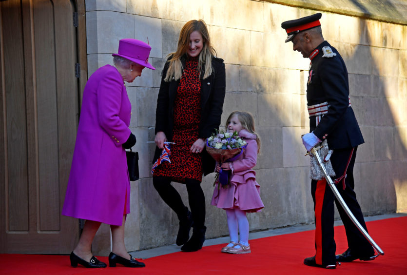 Evie Hayden, aged 4, and her mother Michelle, present Queen Elizabeth II, with a bouquet of flowers following her visit to The Honourable Society of Lincoln's Inn in London to officially open its new teaching facilit.