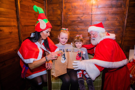 Gayle aka a sort of elf, helps Santa hand over pressies to sister Niamh (9) and Alannah (4) Cullen.