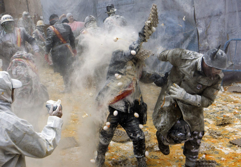 Visitors celebrate with a battle using flour, eggs and firecrackers, outside the city town hall.