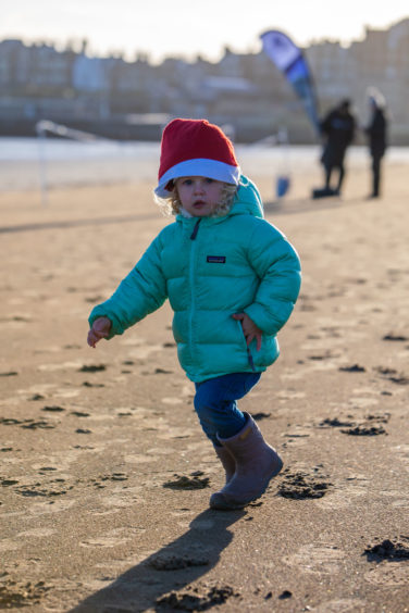 Two-year-old Vega Kerr runs off the start chasing the Santas down the beach.
