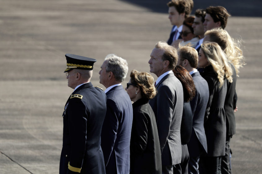 Family members of former President George H.W. Bush, including former President George W. Bush, second from left, watch as members of the military carry the casket to Special Air Mission 41at Ellington Field during a departure ceremony for a state funeral,2018. President George H.W. Bush died last week in Maine. The painting was done by his son and former 43rd President George W. Bush.