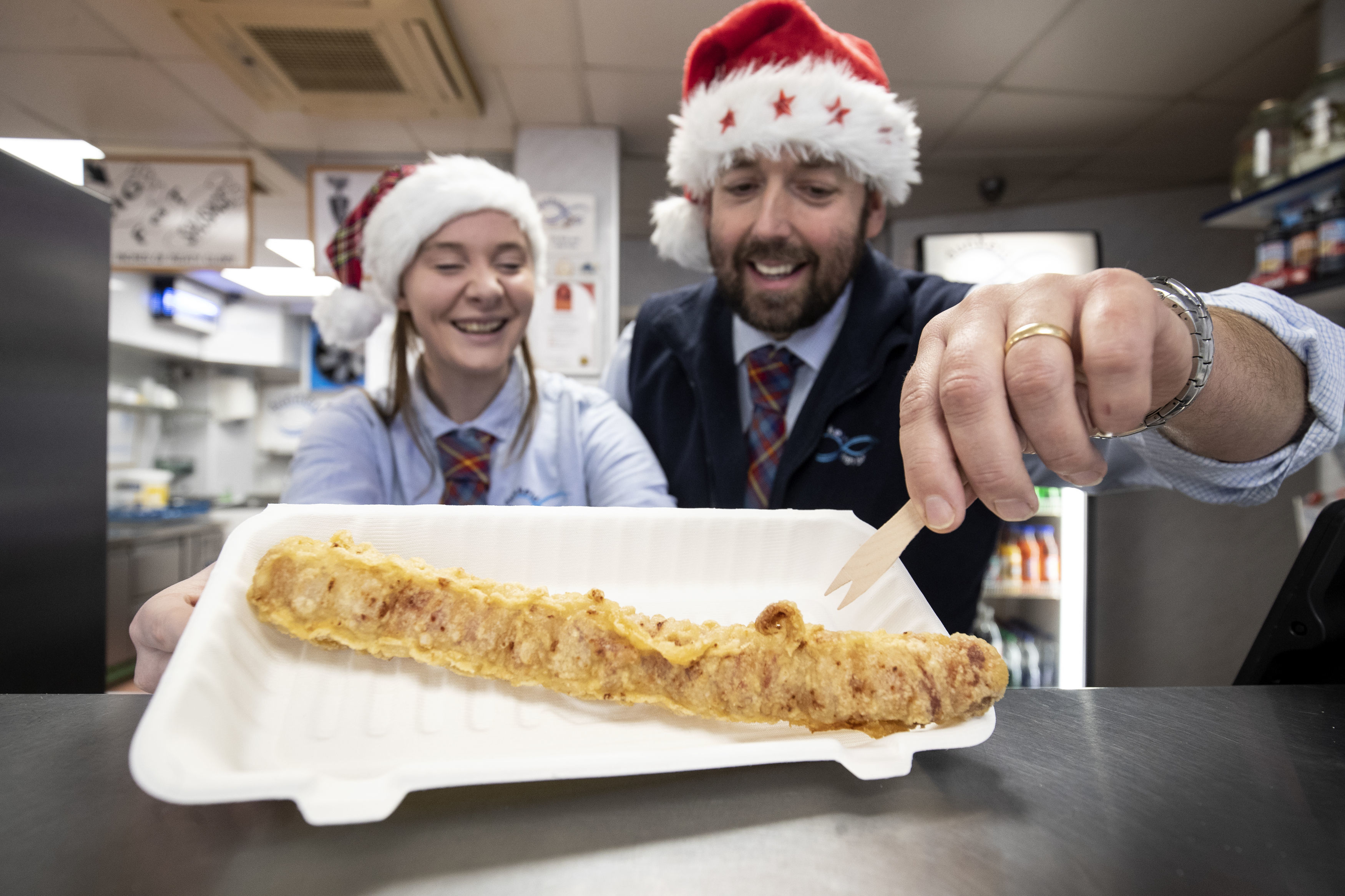 Chelsea McGowan and chip-shop owner Scott Davie serve up a deep-fried pig-in-blanket.