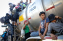 People from a caravan of Central American migrants climb onto a tanker truck they were hoping to catch a ride from, on their way toward the United States, .Some members of the caravan are in Mexico while others are further behind in Guatemala.